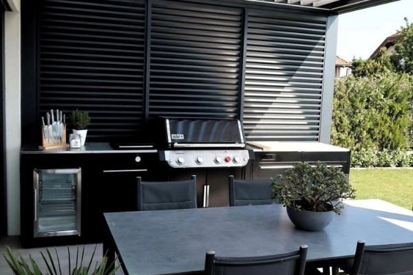 Masa cu scaune si bucatarie de exterior BBQ Kitchen pe terasa acoperita.